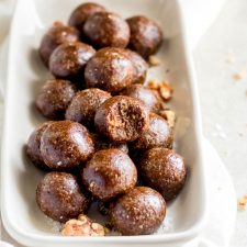 A plate of gingerbread balls, one on top has a bite out of it.