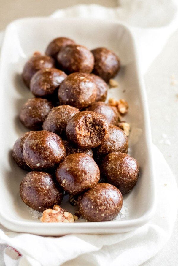 A plate of gingerbread balls, one on top has a bite out of it.