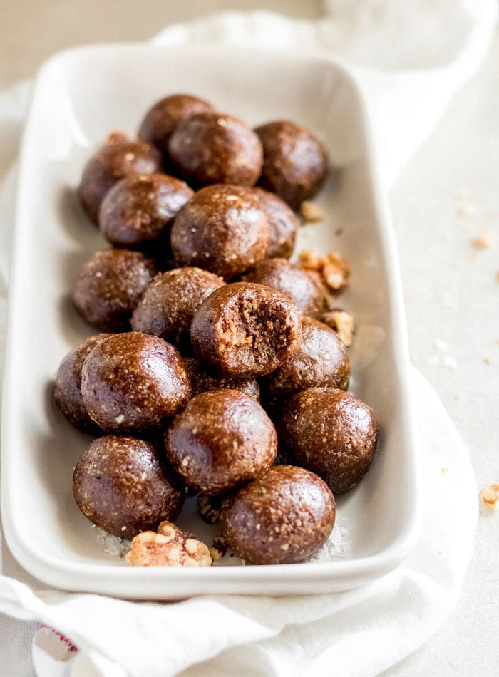 A plate of gingerbread balls, one on top has a bite out of it.