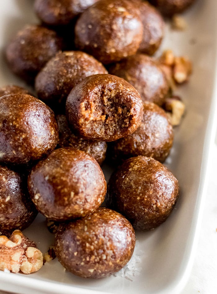 Close up of raw gingerbread balls on a tray, one on top has bite out of it.