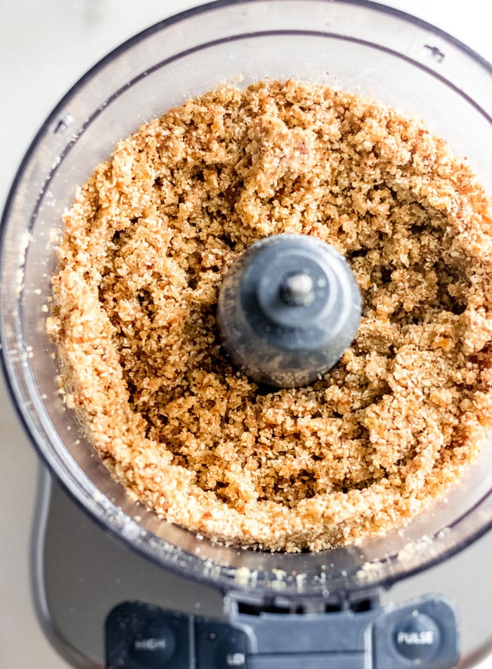 A crumbly, blended dough in a food processor container.