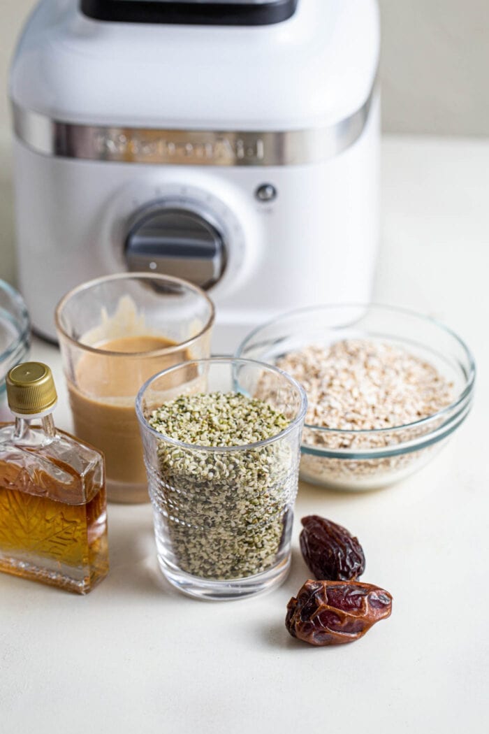 Hemp seeds, tahini, coconut, dates and maple syrup sitting on a counter top.