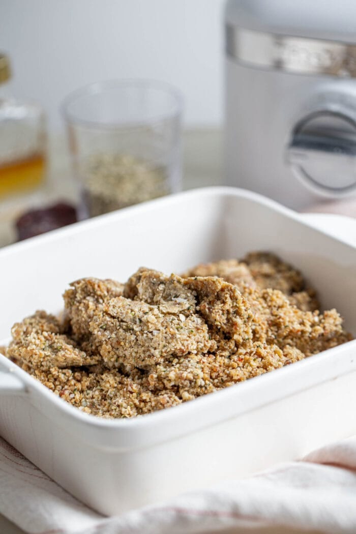 Crumbly dough with hemp seeds in a square baking dish.