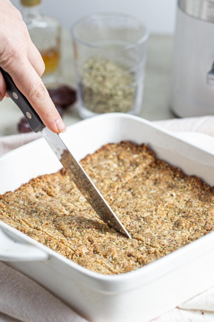 A knife cutting into bars in a baking dish.