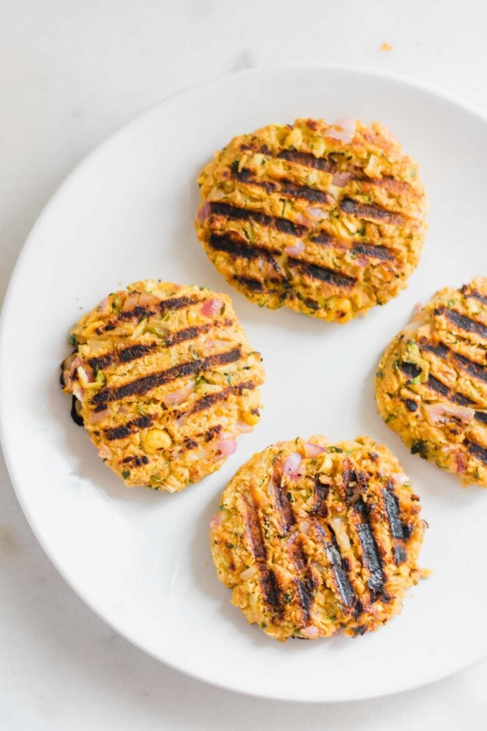 4 cooked chickpea veggie burger patties on a plate.