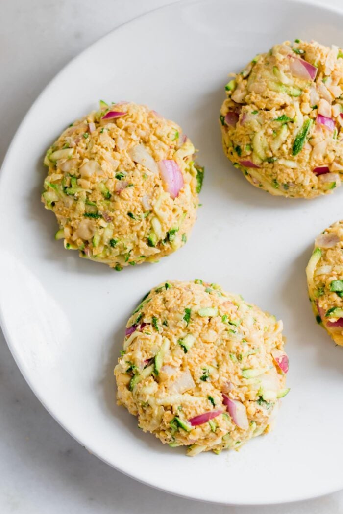 4 raw veggie burger patties on a plate.