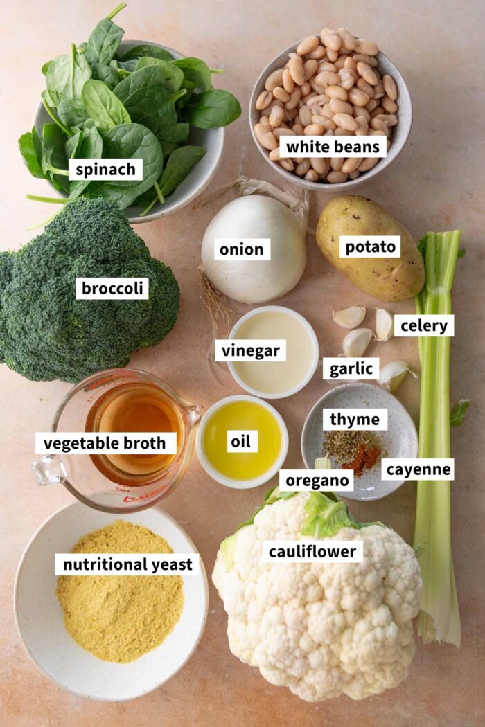 All the ingredients laid out for making a vegan cauliflower broccoli soup recipe with white beans, onion, celery, nutritional yeast and potato.