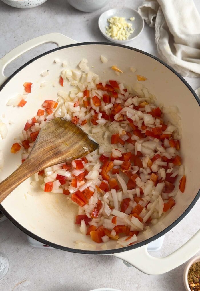 Diced onion and bell pepper cooking in a pot.
