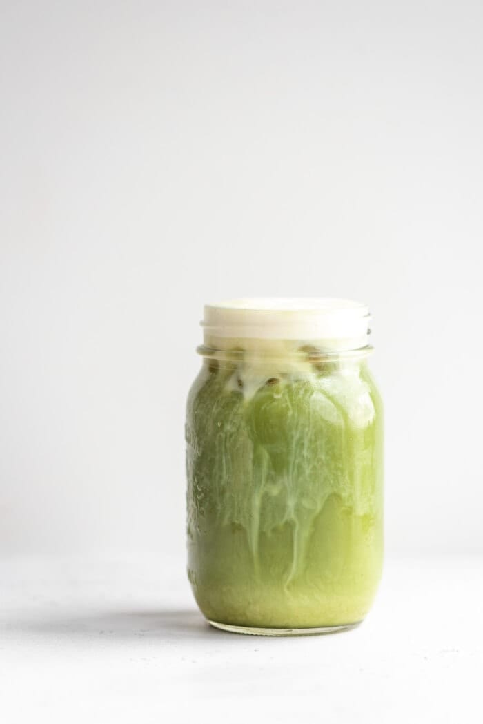 Jar of iced matcha on a grey background.