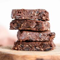 A close up of a stack of 4 raw brownies on a cutting board.