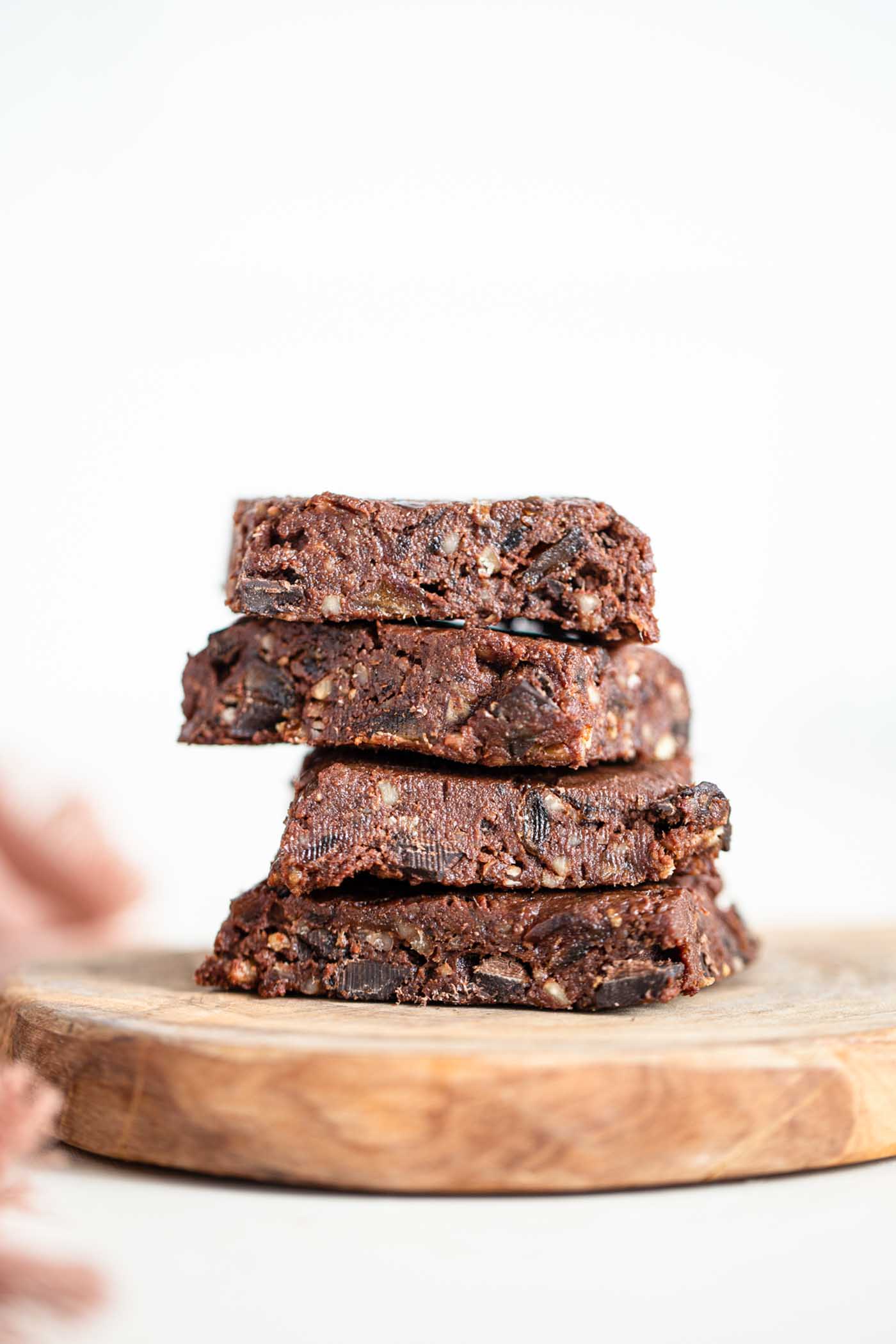 A stack of 4 raw brownies on a cutting board.