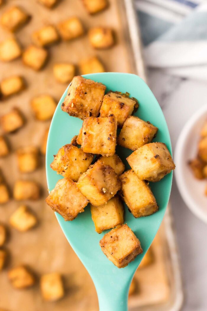 Cubes of crispy tofu on a silicone spoon.