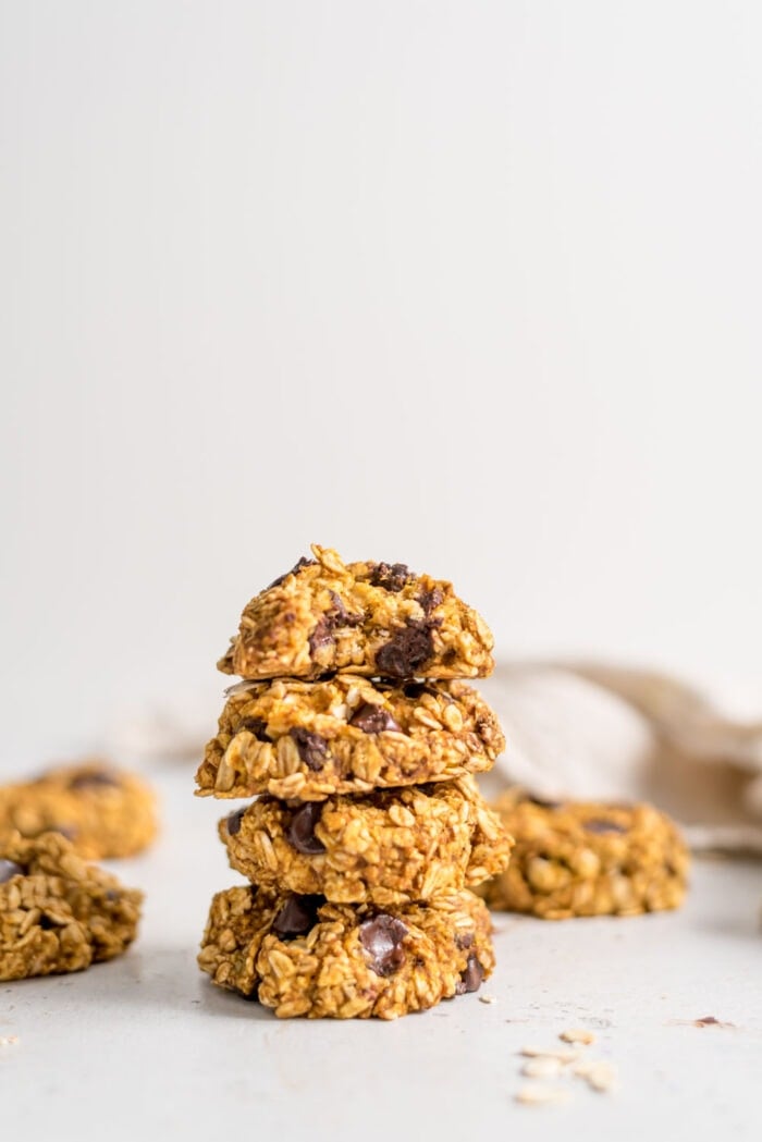 A stack of pumpkin chocolate chip cookies with a bite out of the one on top.