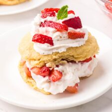Strawberry shortcakes topped with a small piece of mint on small round plates.