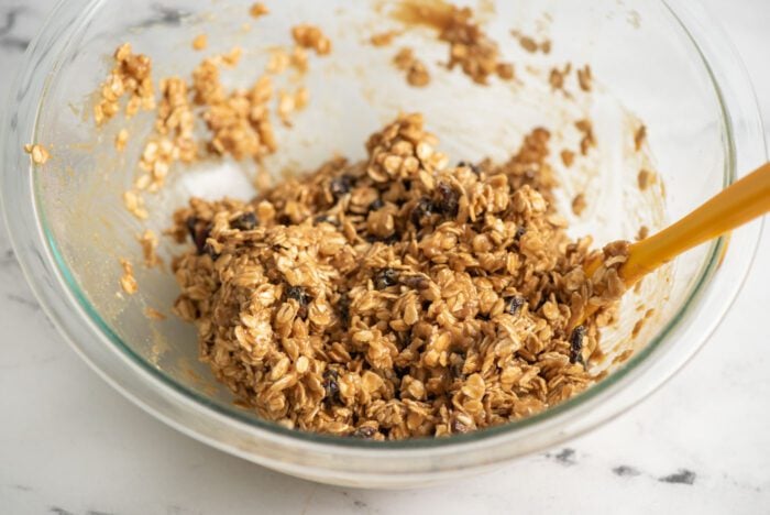 Oatmeal cookie dough with cranberries and walnuts in a glass mixing bowl.