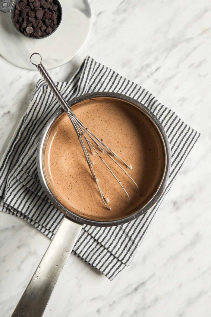 Whisk sitting in a small saucepan of hot chocolate.