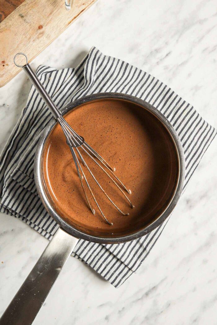 Whisk sitting in a small saucepan of hot chocolate.