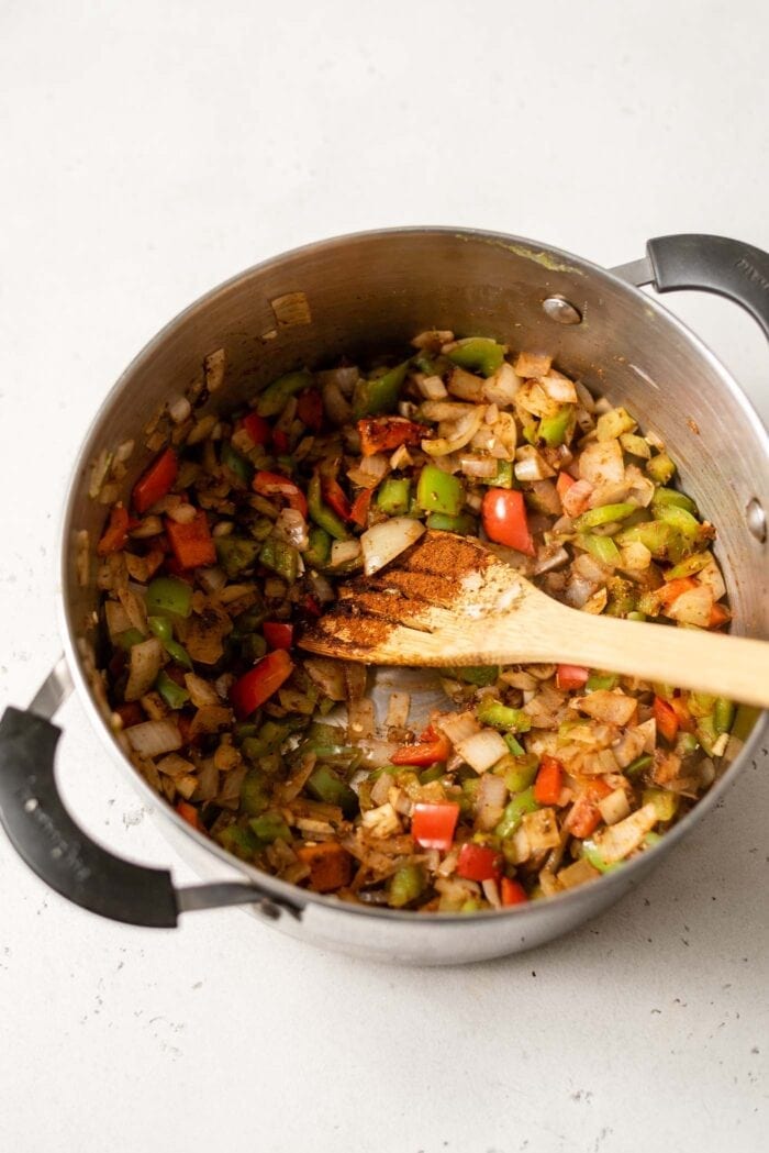 Bell peppers, onion and garlic being cooked in a large soup pot.