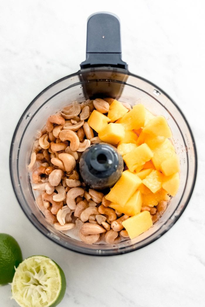 Raw cashews and mango in a food processor.