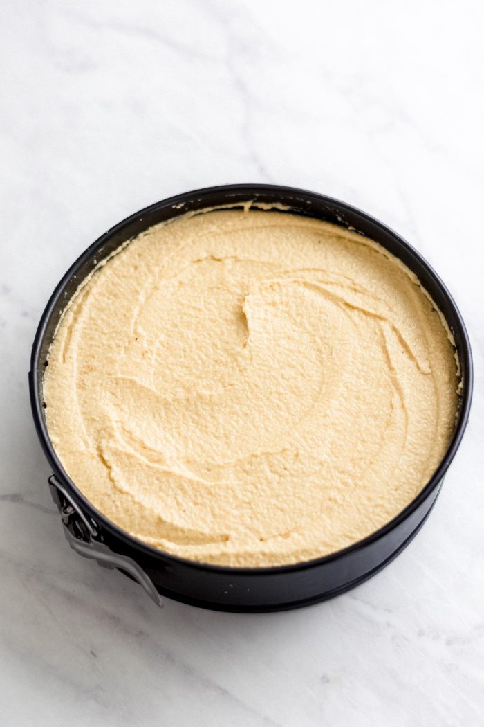 Raw mango cheesecake filling in a springform cake pan.