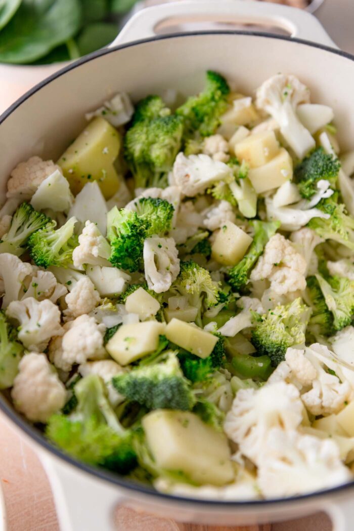 Broccoli, cauliflower, potato and onion cooking in a large pot.