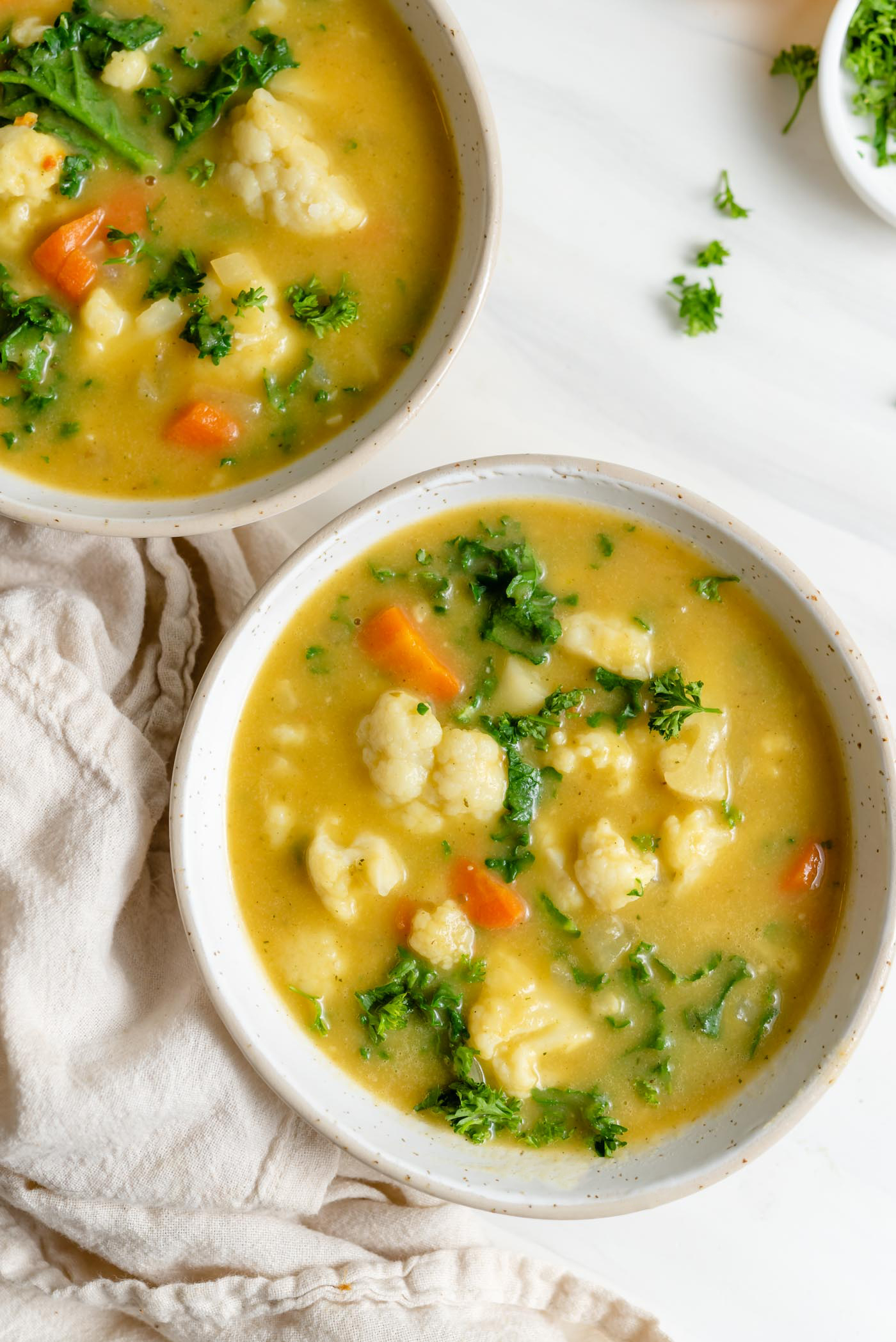 Overhead view of two bowls of kale cauliflower carrot soup.