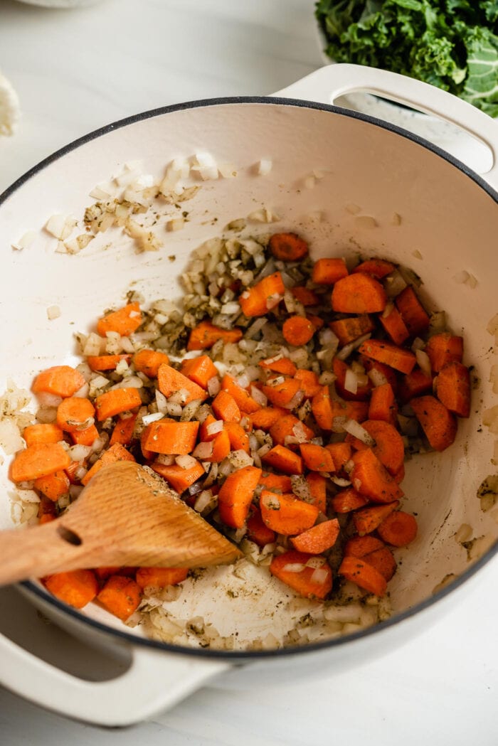 Chopped carrots, onion and garlic cooking in a large soup pot.
