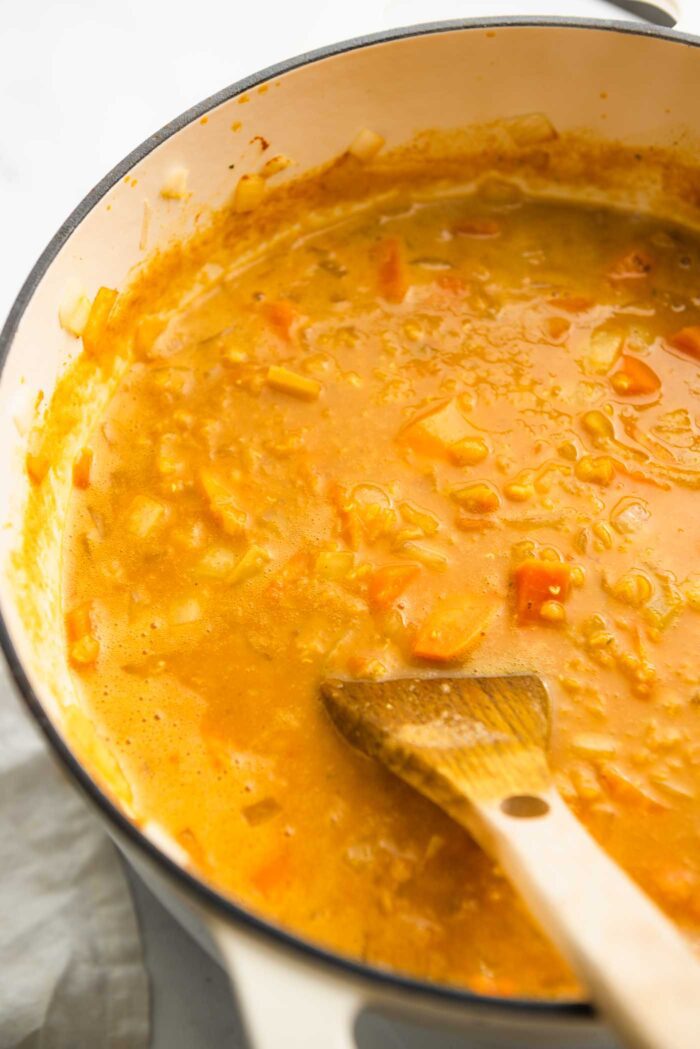 A creamy sweet potato red lentil soup cooking in a large soup pot.