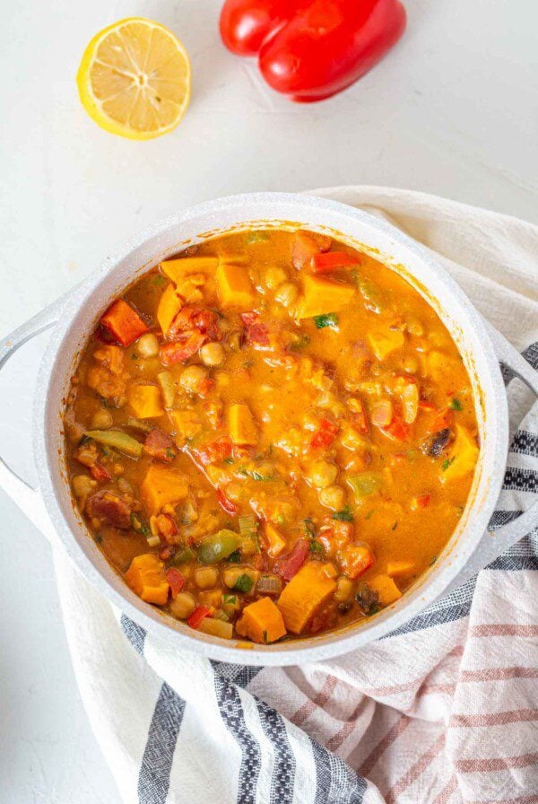 A large pot of sweet potato stew sitting on a dish towel.