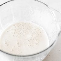 Large glass measuring cup with hemp seed milk in it.