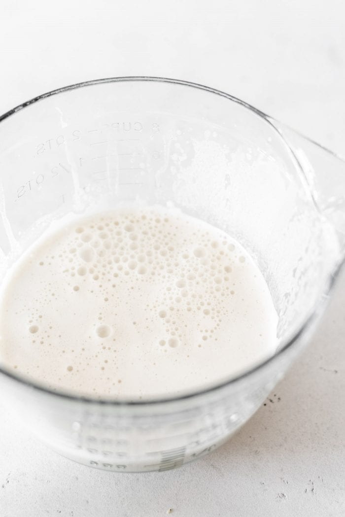 Large glass measuring cup with hemp seed milk in it.