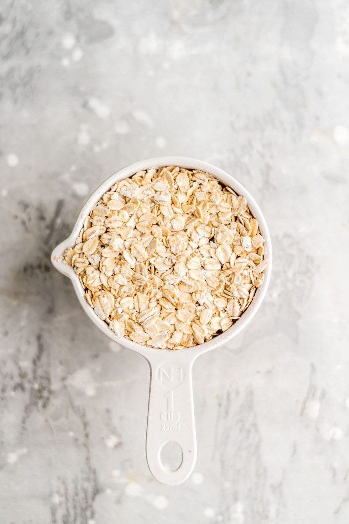 1 cup of rolled oats in a white measuring cup for making oat milk.