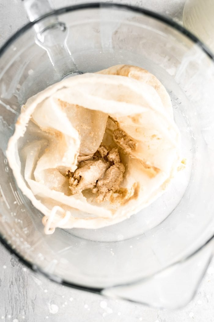 Leftover over oat milk pulp in a nut milk bag from making homemade oat milk.