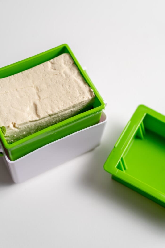 A block of tofu in a tofu press.