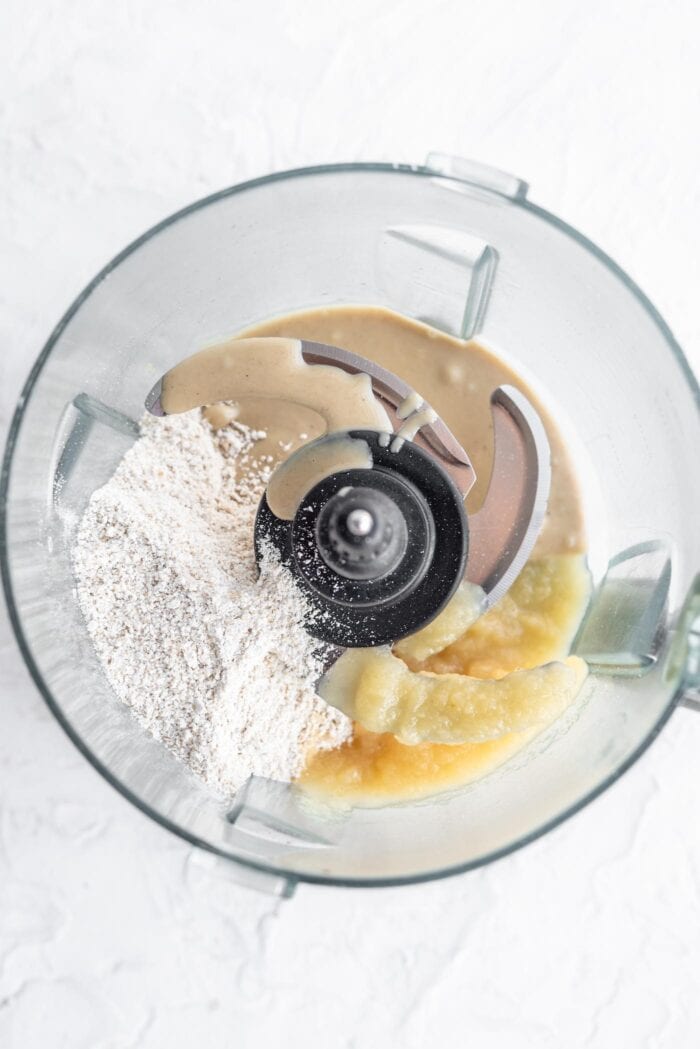 Oat flour, applesauce and tahini in a food processor container.