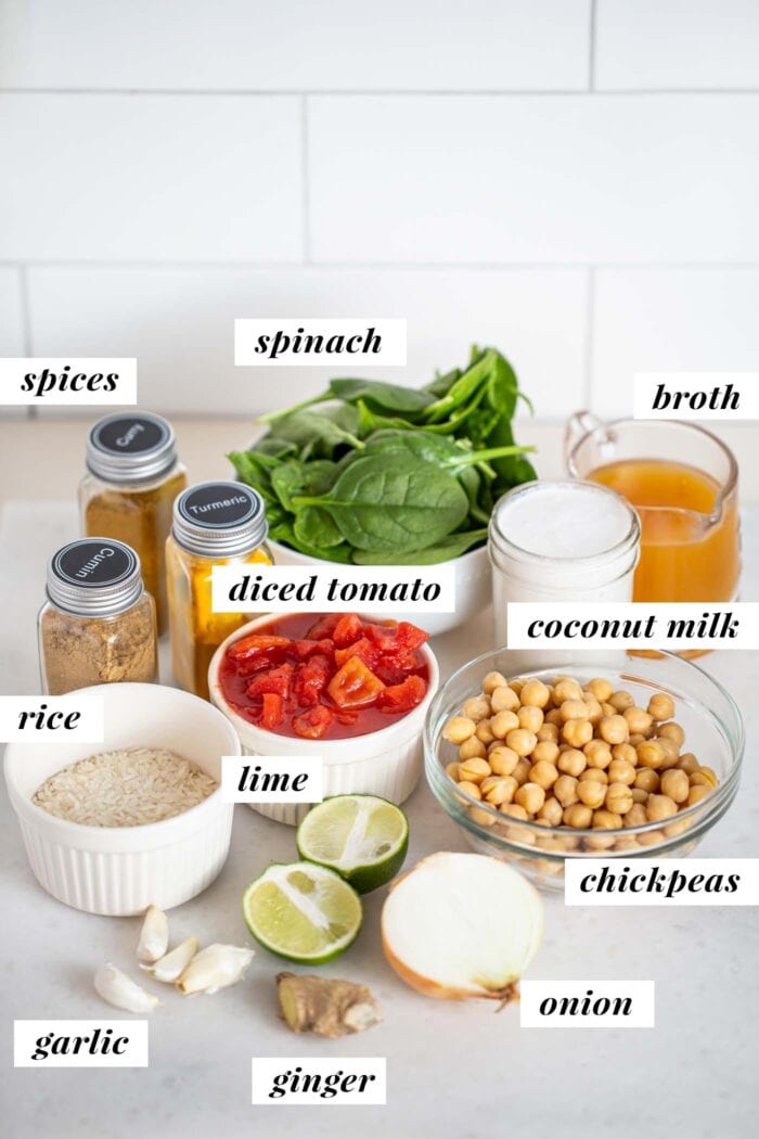 Labelled ingredients in various small bowls for making a tomato rice and chickpea stew.