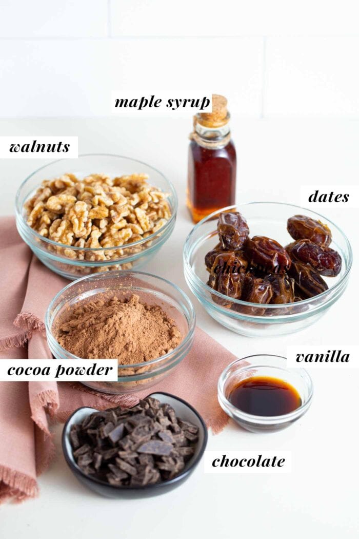 Chocolate, cocoa powder, walnuts, dates and vanilla in labelled containers.