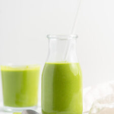 Green smoothie in a jar with another smoothie in the background.