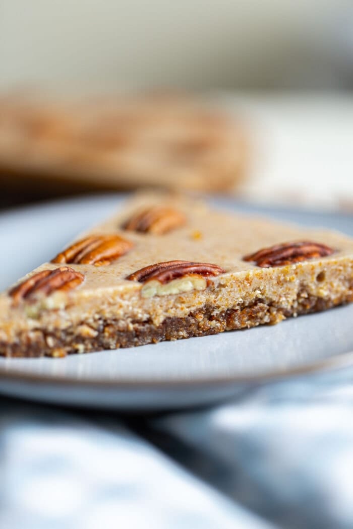 A slice of raw maple pecan pie on a small blue plate.