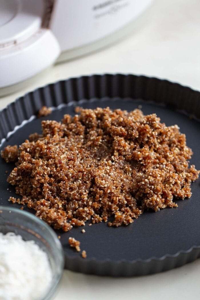 Crumbly no-bake raw pie crust in a small pie dish.