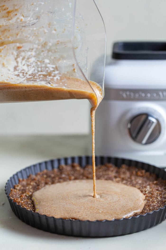 Pouring a no-bake pie filling onto a pie crust.