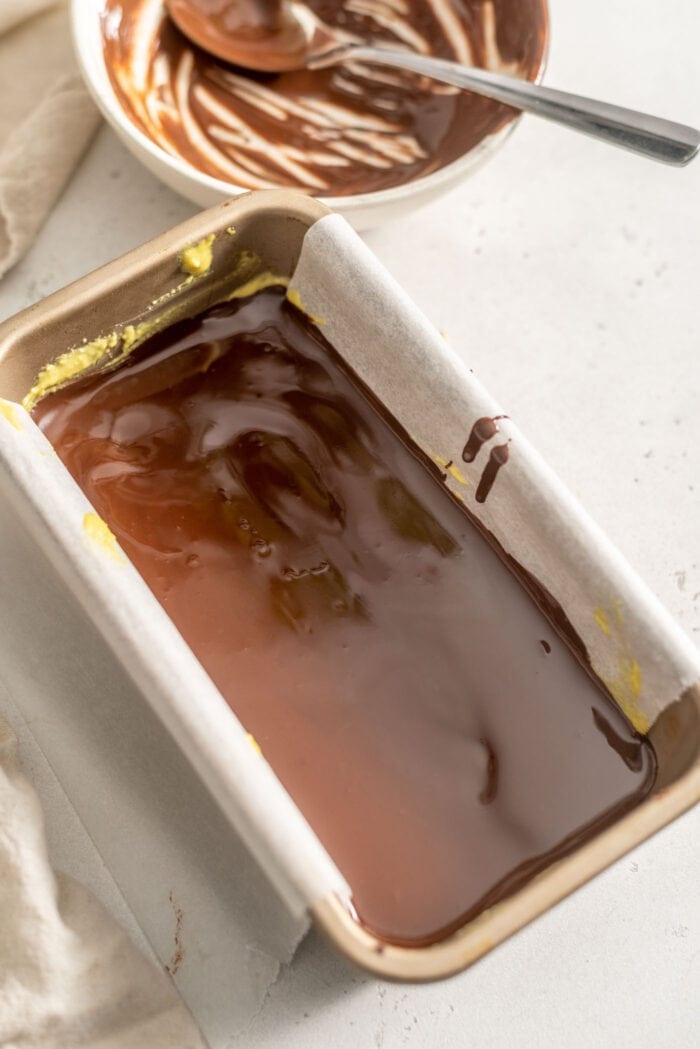 Melted chocolate in a loaf pan lined with parchment paper.