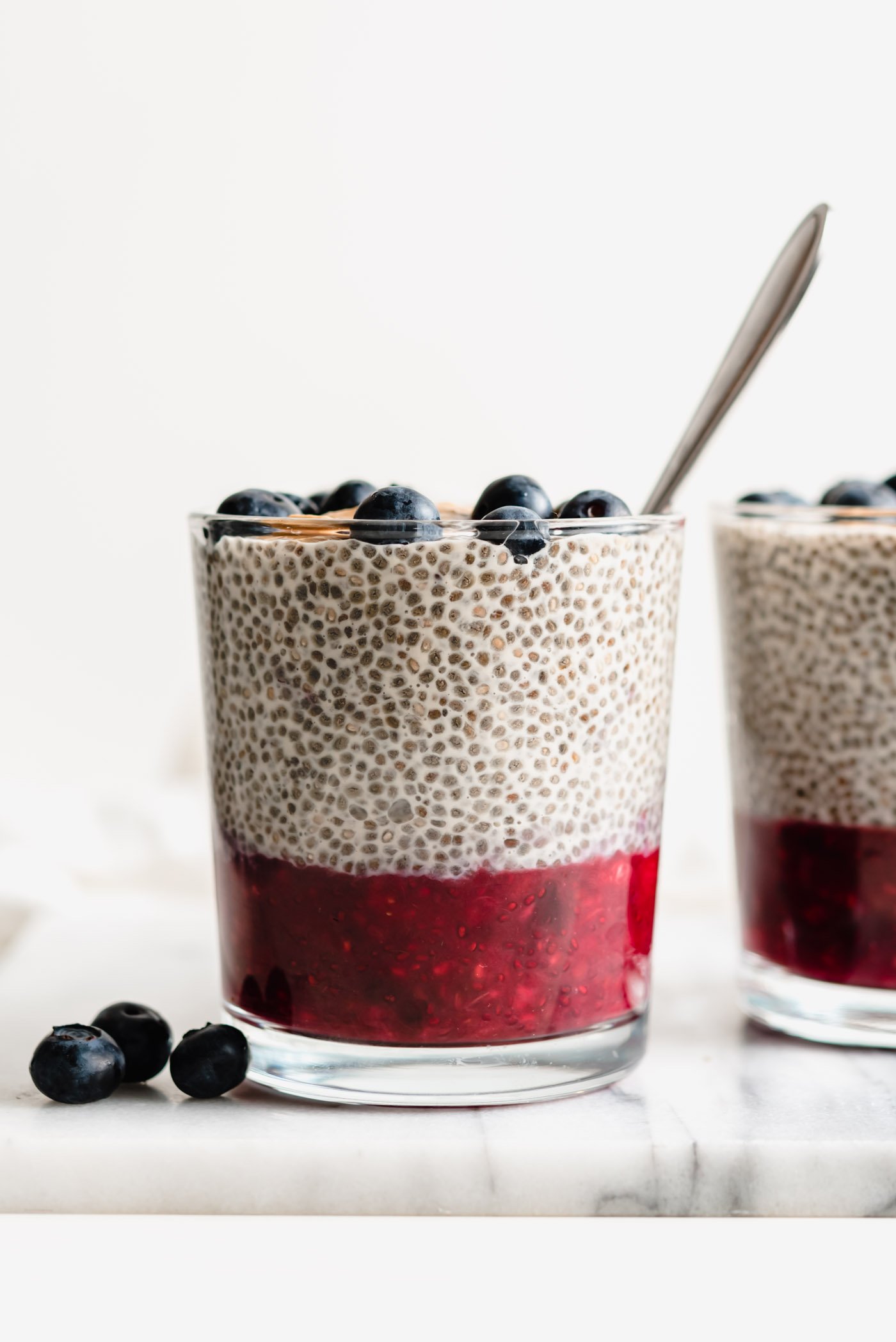 Two jars of peanut butter chia pudding with a layer of jam on the bottom of the jars.