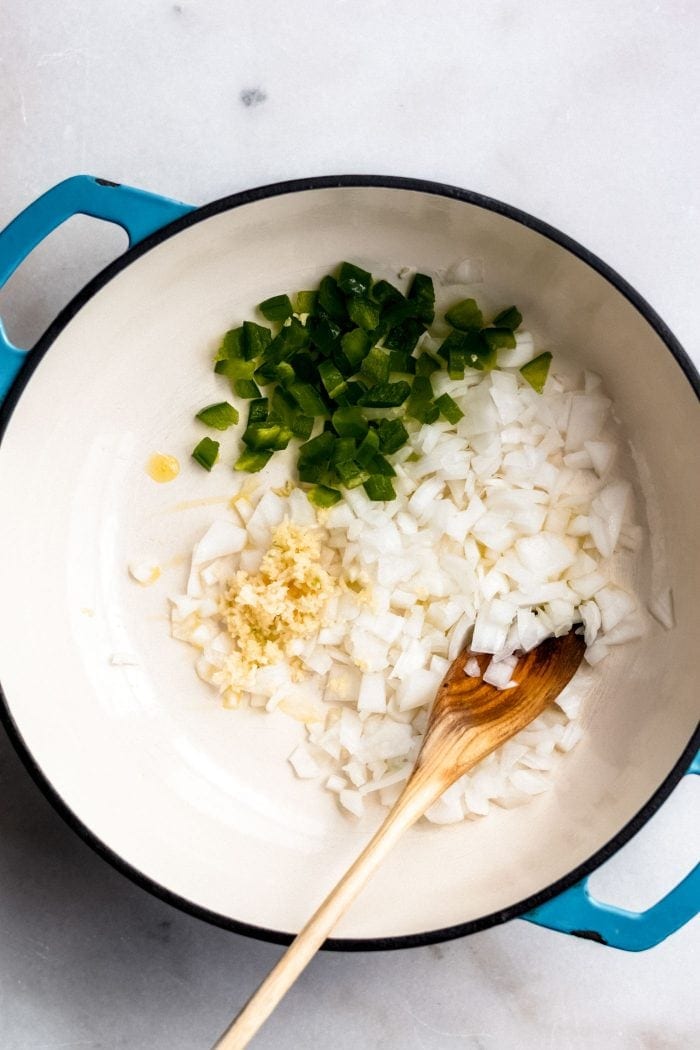 Onions, garlic and jalapeno cooking in a soup pot for making vegan tortilla soup.