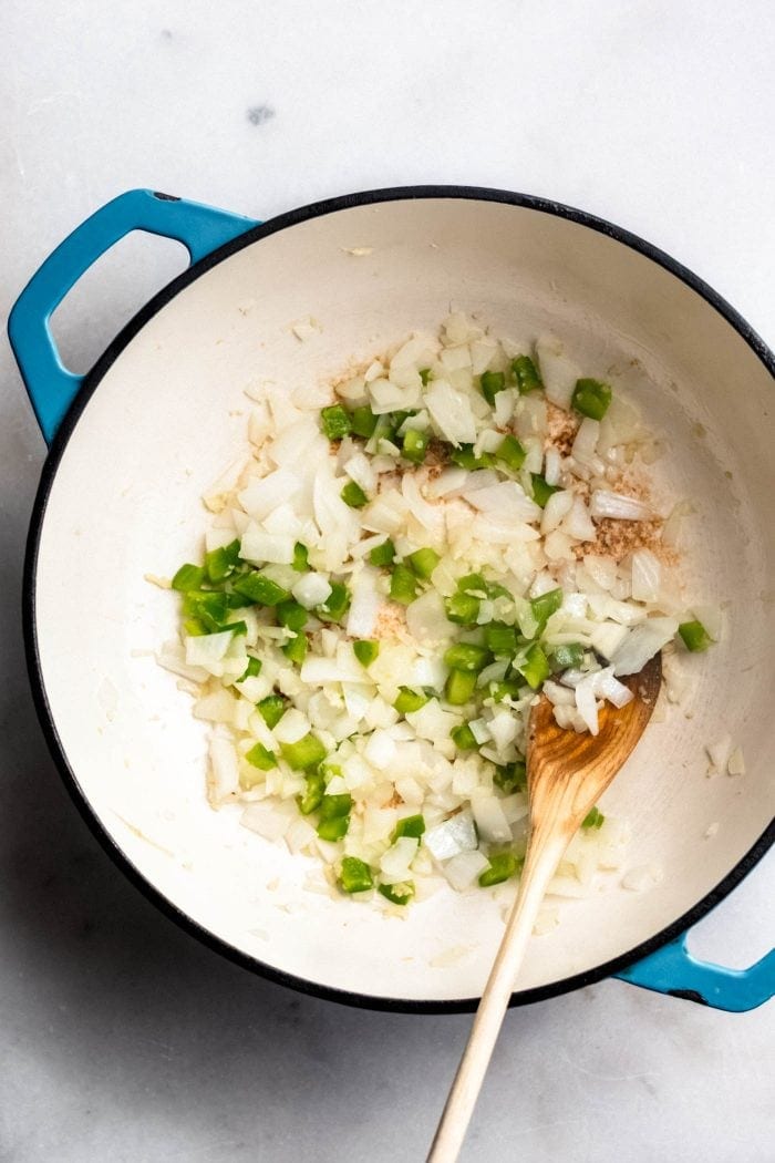 Onions, garlic and jalapeno cooking in a soup pot for making vegan tortilla soup.