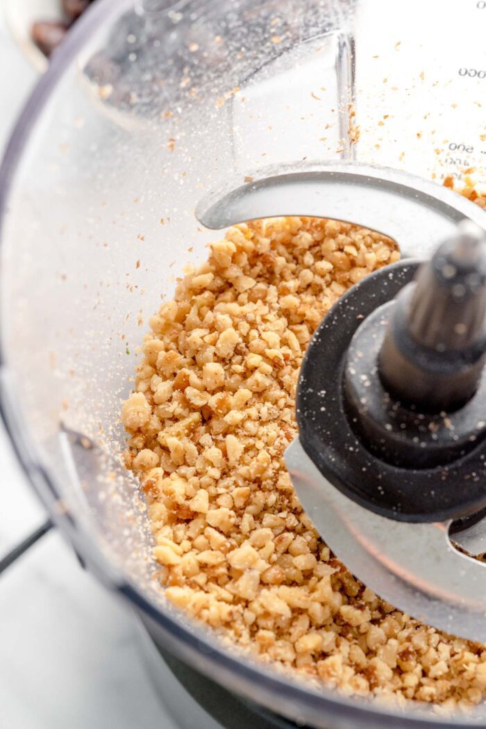 Blended raw walnut pieces in a food processor container.