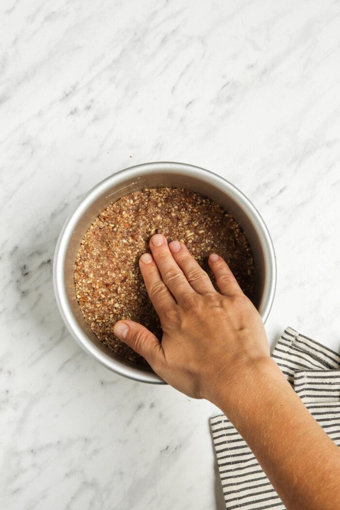 Hand pressing dough into a pie tin to create the crust.