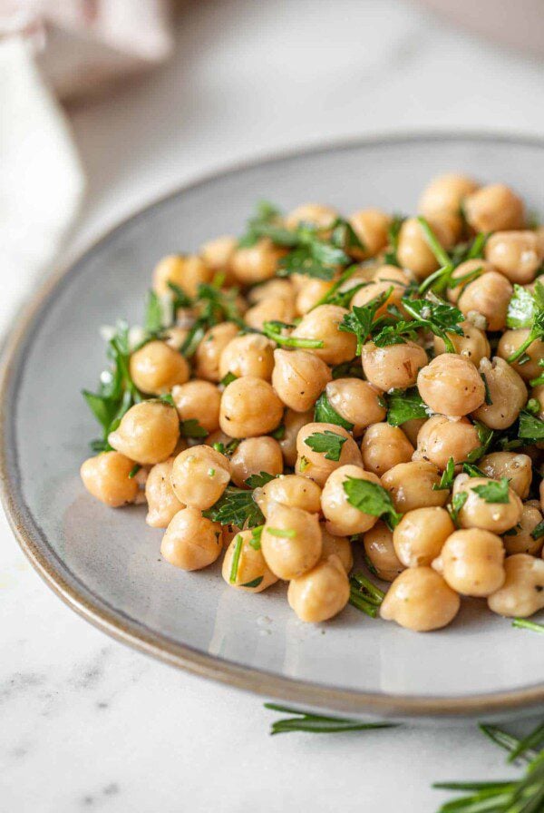 A simple chickpea salad with chopped herbs and garlic on a small plate.