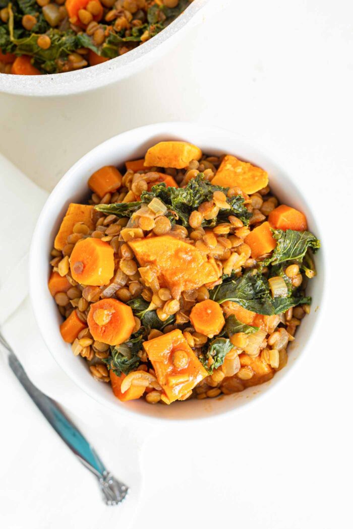 Overhead image of a bowl of sweet potato lentil stew with kale mixed into it.