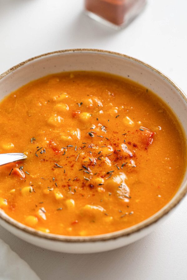 Close up of a sweet potato corn chowder in a bowl. Spoon rests in bowl.